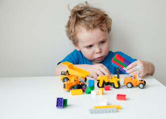 Boy plays colorful multi-colored cubes and cars on the table. Early development and learning. 