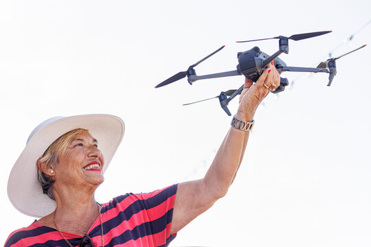 Anziana signora con un cappello tiene insano divertita un drone
