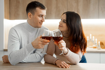 happy married guy husband and girl wife drinking red wine celebrate together at home