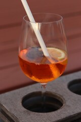 Vertical shot of an exotic fruity drink with a paper straw put on a glass holder