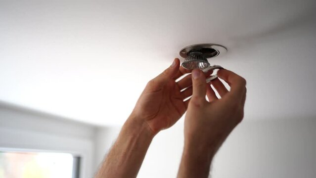 Man (unrecognizable) replacing a LED spotlight on a ceiling. 