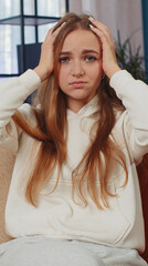 Fototapeta premium Sad girl at home looks pensive thinks over life concerns or unrequited love, suffers from unfair situation. Young woman problem, break up, depressed feeling bad annoyed, burnout. Vertical screen view