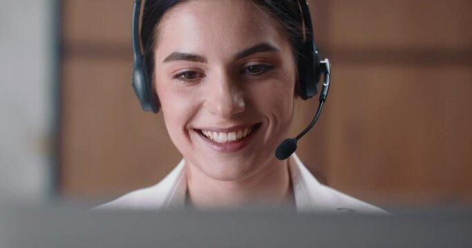 Young caucasian woman provides tutor service and conducts individual online lesson while sitting at laptop. Female tutor laughs and smiles while explains topic of the lesson and teaches her subject.