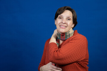 Woman in an orange sweater in the studio. High-quality photo was taken on a blue background with a campy pose.