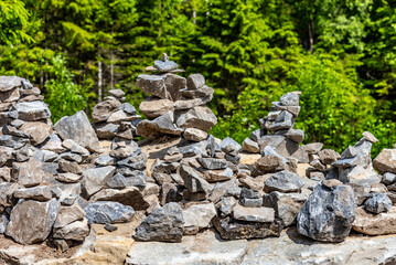 Fototapeta na wymiar Pyramids of stones in Karelia. Pyramids of stones on background of green forest. Natural stones on top of each other. Balancing stones in the forest.