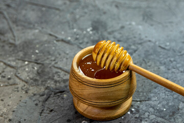 Fresh liquid honey, honey stick on a black background. Wooden utensils with honey