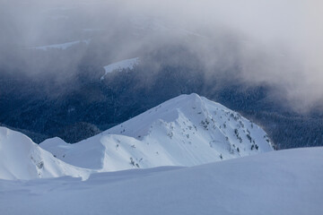 Fog and clouds over a snowy mountain peak