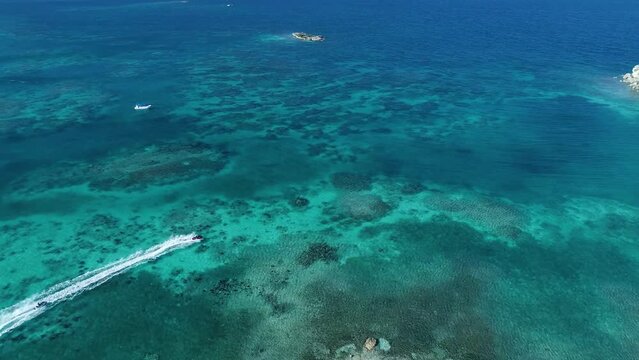 Couple rides jet skis along the tropical coast, aerial view.