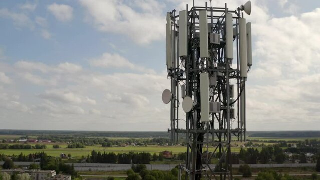 Telecommunication tower 5G near small town and village. Telecom tower antenna and satellite transmits the signals of cellular 5g and 4g mobile signals. High quality 4k footage