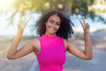 Winner girl spending a day in a park doing the victory sign