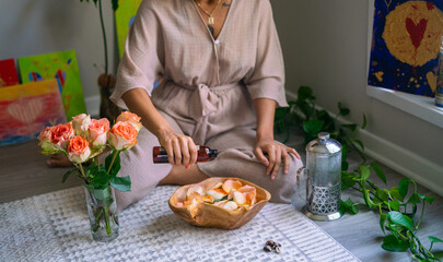 Young woman pouring oil into bowl flowers