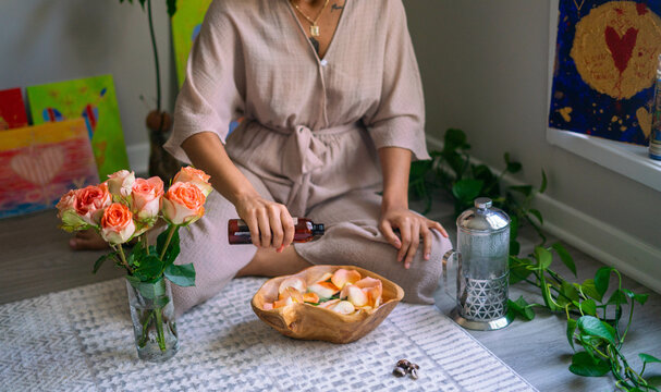 Young woman pouring oil into bowl flowers