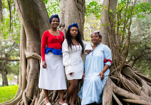 Haitian women sitting in tree in traditional colors