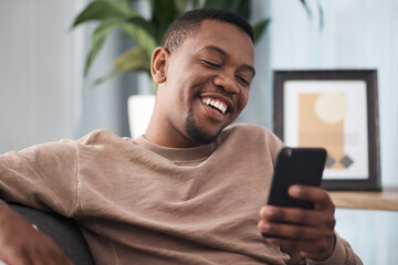 Happy, phone and man in a living room texting, laughing and reading social media post in his home. Day off, black man and online chat on smartphone, text and funny message on dating website or app - obrazy, fototapety, plakaty