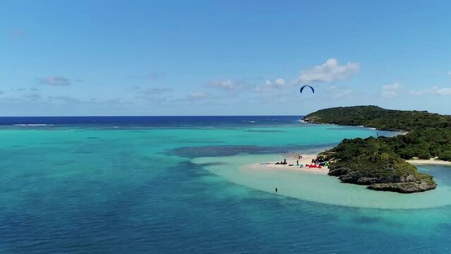 Kitesurfing in turquoise water of tropical beach paradise in warm waters at bright sunny day. Aerial view