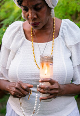 Woman in garden with candle and rosary