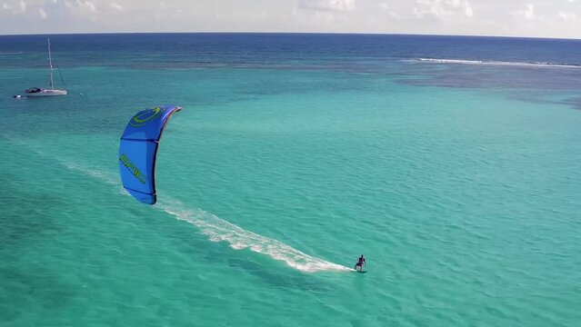 Kitesurfing in turquoise water of tropical beach paradise in warm waters at bright sunny day. Aerial view