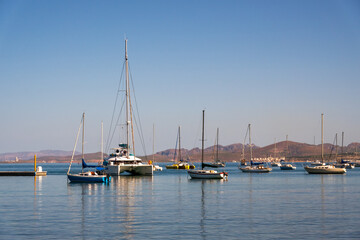 A large catamaran yacht (multi-hulled watercraft) enters the moorage off the Malecon (waterfront walkway) in La Paz, Baja de California Sur, Mexico. 