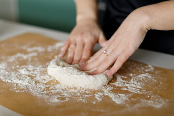 Women's hands knead the dough for homemade baking, a recipe for cookies or bread.