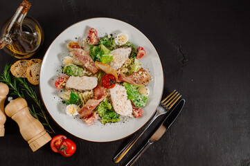 Tasty fresh salad ceasar with ham and vegetables on black background