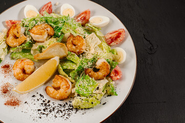 Tasty salad with shrimps, herbs and vegetables on black background