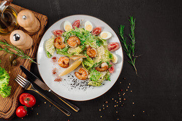 Tasty salad with shrimps, herbs and vegetables on black background