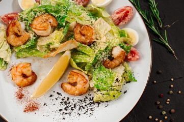 Tasty salad with shrimps, herbs and vegetables on black background