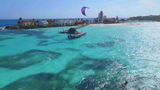 Kitesurfing in turquoise water of tropical beach paradise in warm waters at bright sunny day. Aerial view