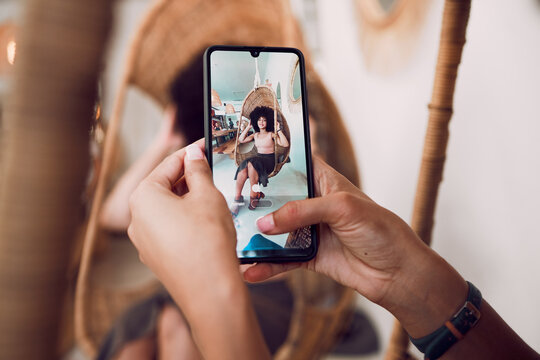 Hands, phone and fashion with a designer taking a photograph of a model black woman in a swing chair. Smartphone, photography and style with an edgy female on screen or display of a design employee