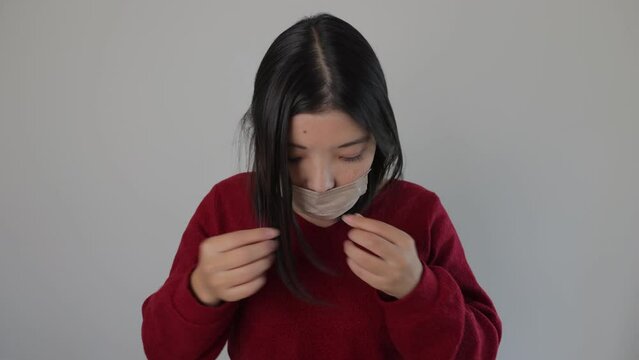 Japanese young woman put a mask on. Tired, Reluctant, Uncomfortable. Dolly in.