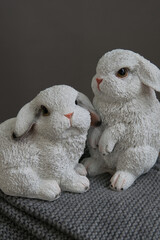 Cute white plastic bunny on grey backgground, selective focus. Home decor