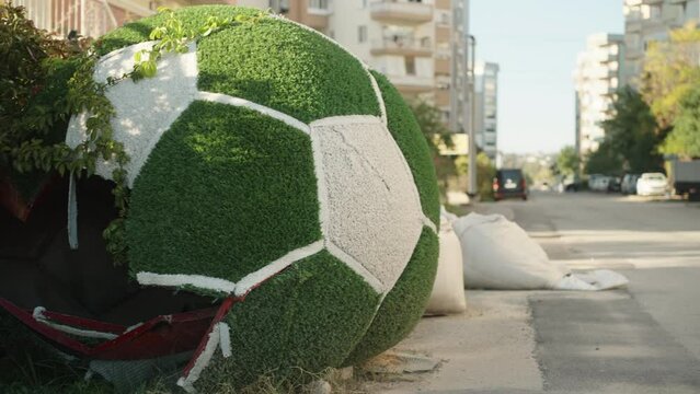 A broken installation made of artificial grass in the form of a soccer ball.