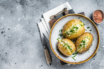 Baked Jacket potatoes with cheese and butter. Gray background. Top view. Copy space