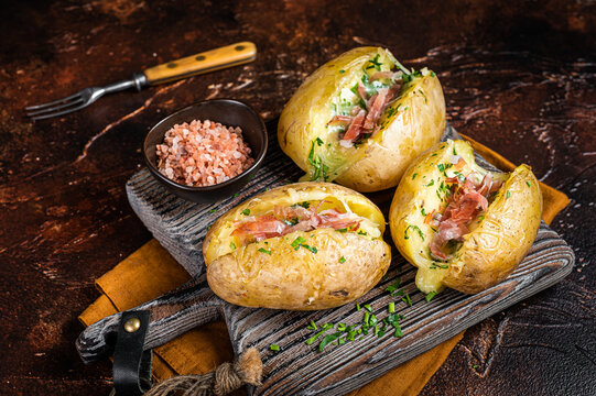 Jacket potatoes baked with cheese, herbs and butter. Dark background. Top view