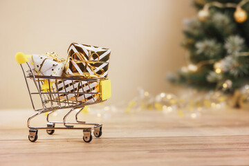 Online christmas shopping and sale. Shopping cart with gift boxes tied golden ribbons and bow on...