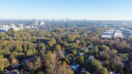 Fototapeta premium Aerial view lush green Brookwood Hills neighborhood with tree-lined streets, residential houses and midtown Atlanta skyscrapers in background