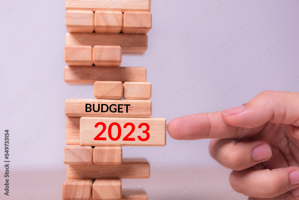 Aufkleber hand insert wood block with text 2023 budget into tower building block