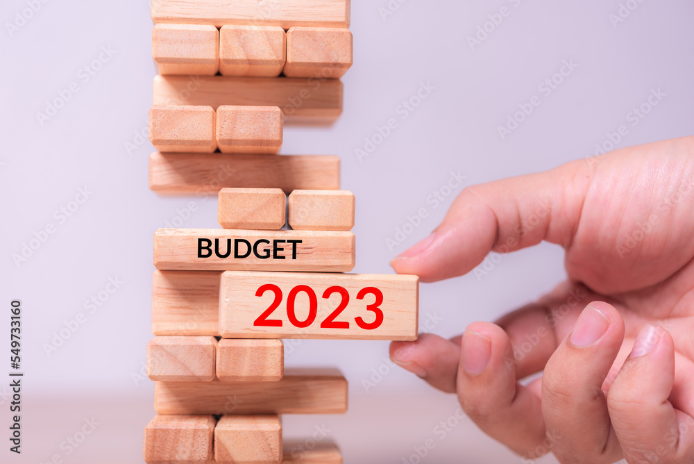 Aufkleber hand insert wood block with text 2023 budget into tower building block