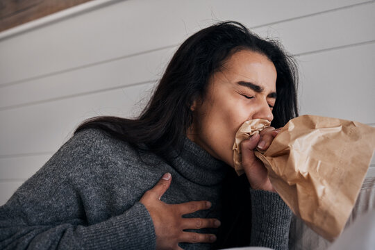 Woman, anxiety and stress paper bag breathing of a woman with mental health problem or crisis. Hyperventilate, panic or fear of a female suffering from chest pain in a rehabilitation centre or home