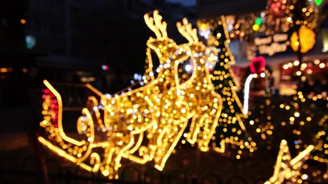 Blurred Christmas lights in the shape of deers and Santa's carriage at outdoor