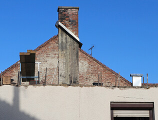 Old house under roof construction against blue sky