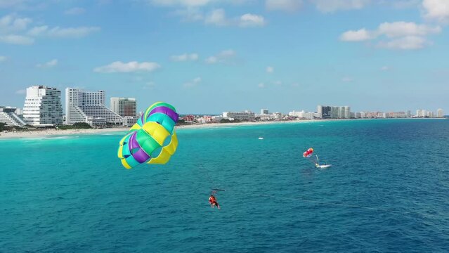 Parasailing aerial view. A couple paraskiing at tropical beach in bright day. 