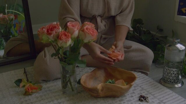 Young woman working with pink rose petals