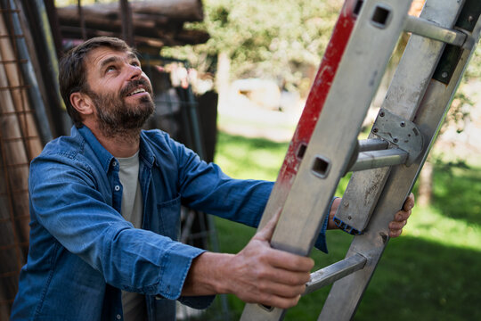 Side view of mature man climbing up the ladder.
