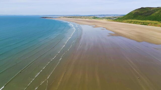 Aerial view flying along a huge and wide sandy beach at low tide