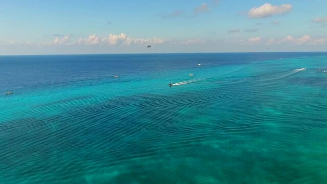 Parasailing aerial view. A couple paraskiing at tropical beach in bright day. 