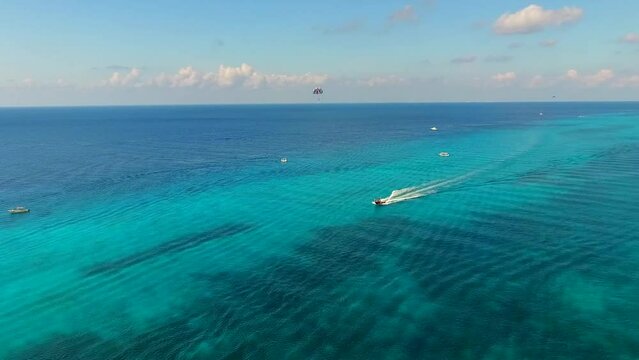 Parasailing aerial view. A couple paraskiing at tropical beach in bright day. 