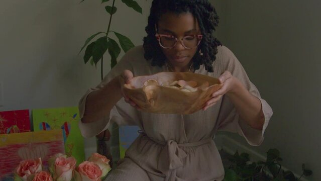 Young woman smelling bowl of flowers and herbs