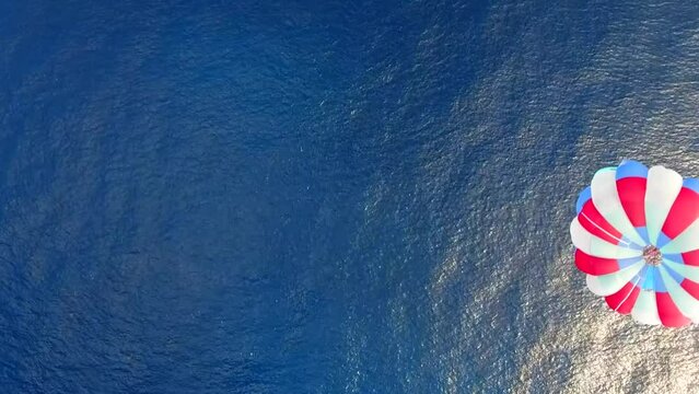 Parasailing aerial view. A couple paraskiing at tropical beach in bright day. 