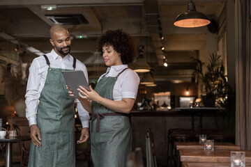 Restaurant owners looking at new menu together on digital tablet